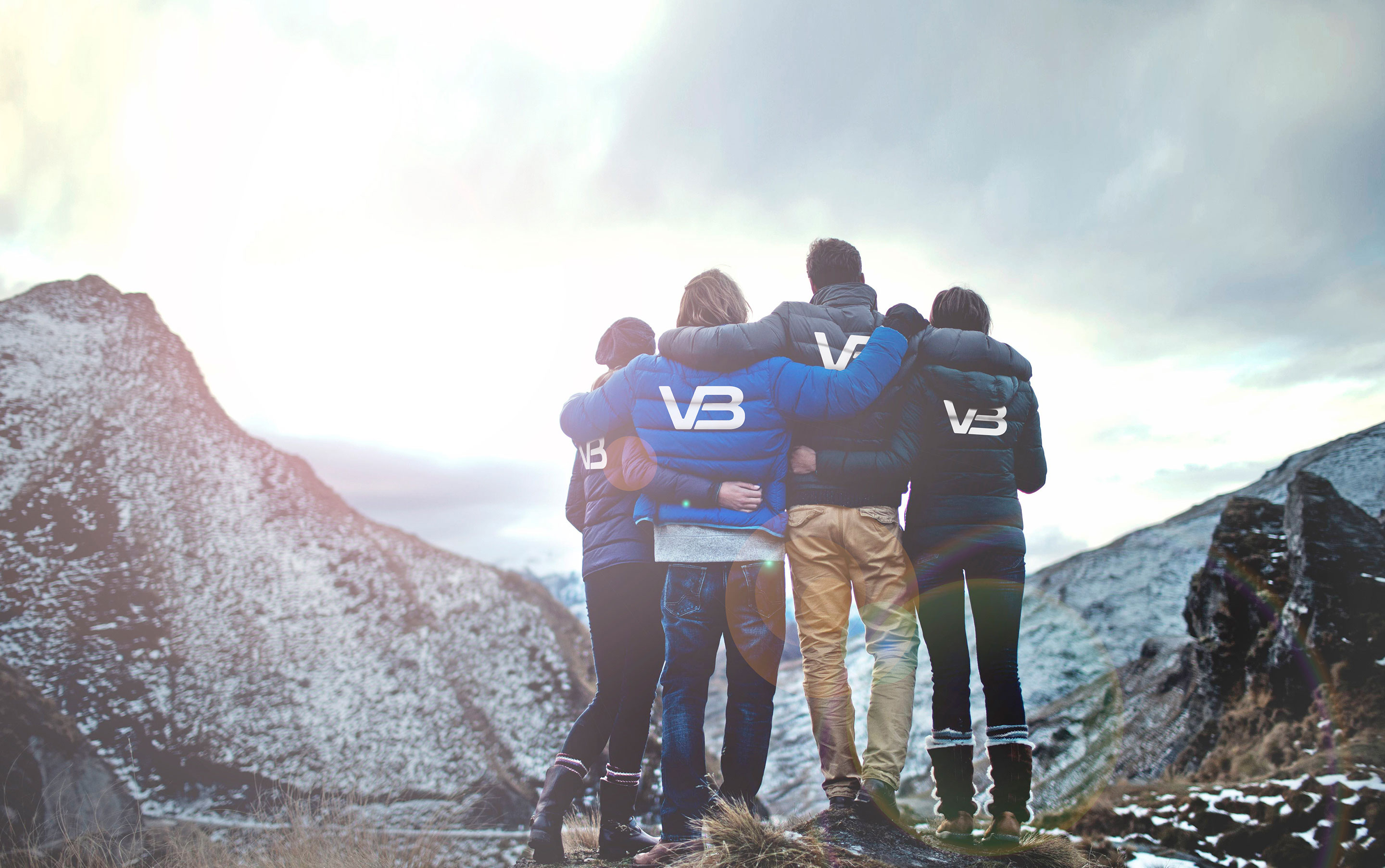Fire VB medarbeidere ser ut mot et fjell. Alle har på jakker med bedriftslogo på baksiden